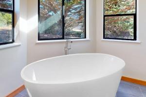 a white bath tub in a bathroom with windows at West Meadow in Sea Ranch