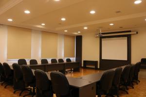 a conference room with a table and chairs and a screen at Villa São Carlos in Caxias do Sul