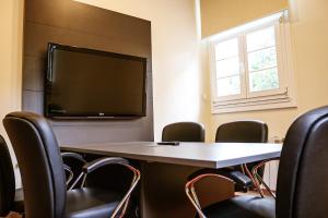 a conference room with a table and chairs and a flat screen tv at Villa São Carlos in Caxias do Sul