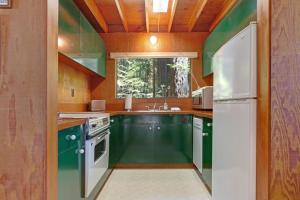 a kitchen with green cabinets and a white refrigerator at Cabin 55 in Sea Ranch