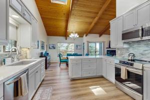 a kitchen with white cabinets and a wooden ceiling at Sea Raven in Gualala
