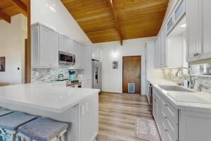 a large kitchen with white cabinets and wooden ceilings at Sea Raven in Gualala