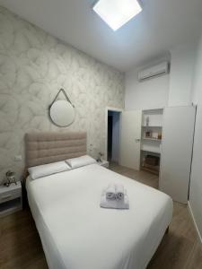 a bedroom with a large white bed with a hat on it at Apartamentos Sal de Luna in Toledo