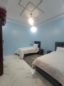 a bedroom with two beds and a ceiling fan at شقق تاج الداخلة in Dakhla