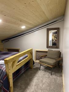 a bedroom with a bed and a chair and a window at Catch'em AK - Bears Den in Soldotna