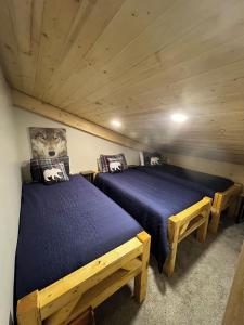 two beds in a room with wooden ceilings at Catch'em AK - Bears Den in Soldotna