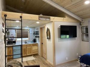 a room with a kitchen with a tv on a wall at Catch'em AK - Salmon Cove in Soldotna