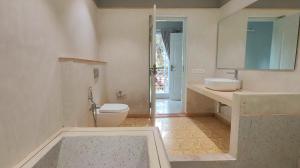 a white bathroom with a toilet and a sink at Plot 77 by hnh in Baga