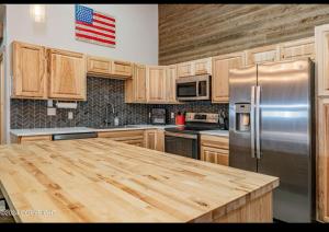 a kitchen with wooden cabinets and a stainless steel refrigerator at Catch'em AK - Eagles Nest in Soldotna