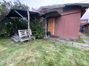 a wooden bench sitting outside of a house at ይሥሓቅ House in Puerto Natales