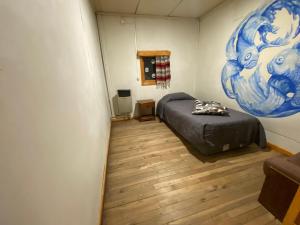 a bedroom with a bed and a painting on the wall at ይሥሓቅ House in Puerto Natales +1 photo
