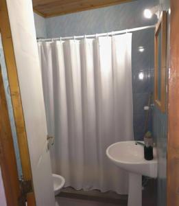 a bathroom with a white shower curtain and a sink at Alquiler la nona in Malargüe