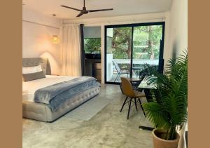 a bedroom with a bed and a balcony with a table at Rico Isla Rooms Eco-Chic in Isla Mujeres
