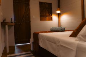 a bedroom with a bed and a lamp and a door at Clan.Destino Hostel in Ilhabela