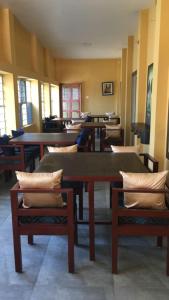 uma sala de jantar com mesas e cadeiras com almofadas em Vajrabodhi Guest House em Bodh Gaya
