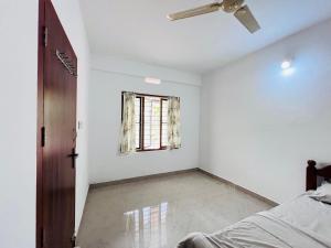 a bedroom with a ceiling fan and a window at HiDot Holidays in Padinjarathara