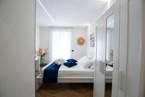 a white bedroom with a bed and a mirror at Residenza sul mare 2 in Naples