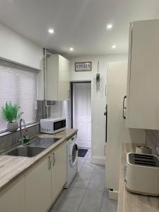 a kitchen with white cabinets and a sink and a dishwasher at Modern Homes in Stoke on Trent +56 photos