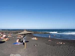 a group of people laying on a beach with an umbrella at La cueva del marinero in El Socorro