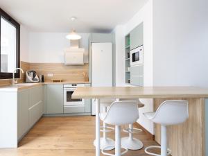 a kitchen with a wooden table and white chairs at Luz de Mafasca in La Hidalga