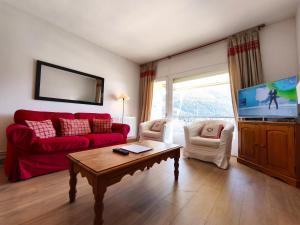 a living room with a red couch and a tv at AC Apartaments Apollo Soldeu in Soldeu