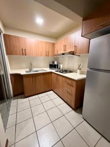 a small kitchen with wooden cabinets and a refrigerator at Hermosa casa en Jiutepec in Jiutepec