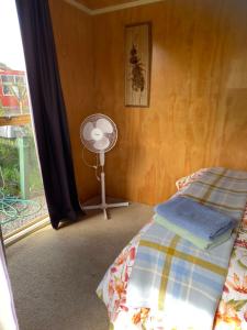 a bedroom with a bed and a fan and a window at Waitomo Farmstay - Kiwi Cabin 5 in Waitomo Caves