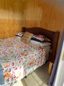 a bedroom with a bed with a floral comforter at Waitomo Farmstay - Kiwi Cabin 5 in Waitomo Caves +5 photos
