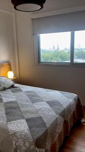 a bedroom with a checkered bed and a window at Urbano Alem in Coronel Suárez