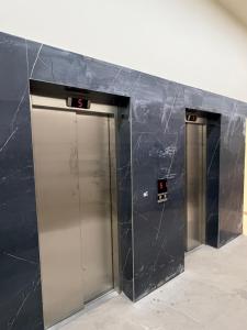 two silver elevators in a black wall at Tirana Urban Nest in Tirana