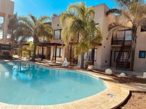 a swimming pool in front of a building with palm trees at Complejo Anjana in Federación