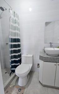 a white bathroom with a toilet and a sink at Sumaran II in Lima