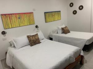 a room with two beds and two paintings on the wall at Hostel La Catalina Plus - frente al mar in Cartagena de Indias +53 photos