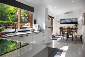 a kitchen with white cabinets and a table with chairs at Little Wombat Daylesford in Daylesford