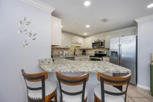 a kitchen with a counter with chairs and a refrigerator at Phoenix X 1504 condo in Orange Beach