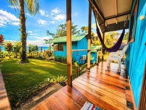 a porch with a hammock and a blue house at Casa Jade in Drake