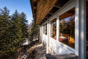 a house with large windows looking out into the woods at Chalet DolceVista con SPA, vicino a Cortina d'Ampezzo in Borca di Cadore