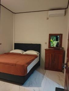 a bedroom with a bed and a dresser with a mirror at Hotel Shandira in Taliwang