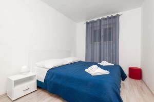 a white bedroom with a blue bed and a window at Apartments with parking space Rabac, Labin - 6464 in Rabac
