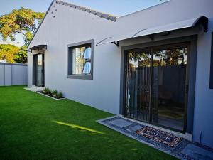 a white house with a yard with green grass at King Deluxe Cottage Room in Cape Town