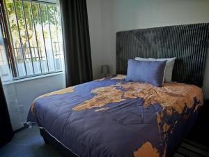a bed with a blue pillow with a map on it at Stylish Studio Room with Shared Pool Near Table View Beach in Cape Town +20 photos