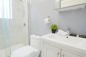 a white bathroom with a shower and a toilet and a sink at Cozy stays in Montreal