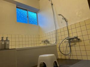 a bathroom with a shower with a stool and a window at Seven base Yoshiumi in Imabari