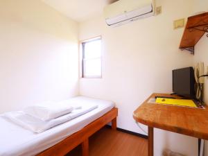 a room with a bed and a desk and a window at House&Cafe GreenTerrace in Ishigaki Island