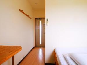 a small room with a bed and a hallway at House&Cafe GreenTerrace in Ishigaki Island