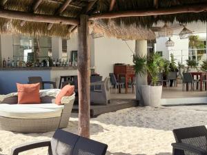 a patio with a couch and chairs on a beach at Condohotel Luciana Deluxe Queen Oceanview Suite with Sofabed in Playa del Carmen