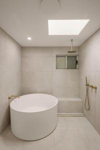 a white bathroom with a tub and a shower at Little Waves Tugun in Gold Coast