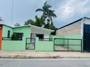a green building with a gate and a palm tree at Estancia Dulce Hogar, en pedernales in Pedernales