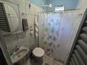 a bathroom with a toilet and a shower curtain at MAEVE Albergue in Goiás