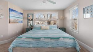 a bedroom with a bed with a blue comforter and two windows at Summer Winds Sanctuary in Cape May
